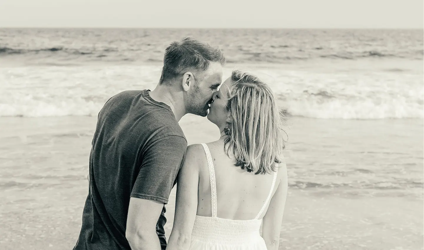 Melissa and Jesse sharing a kiss by the ocean.